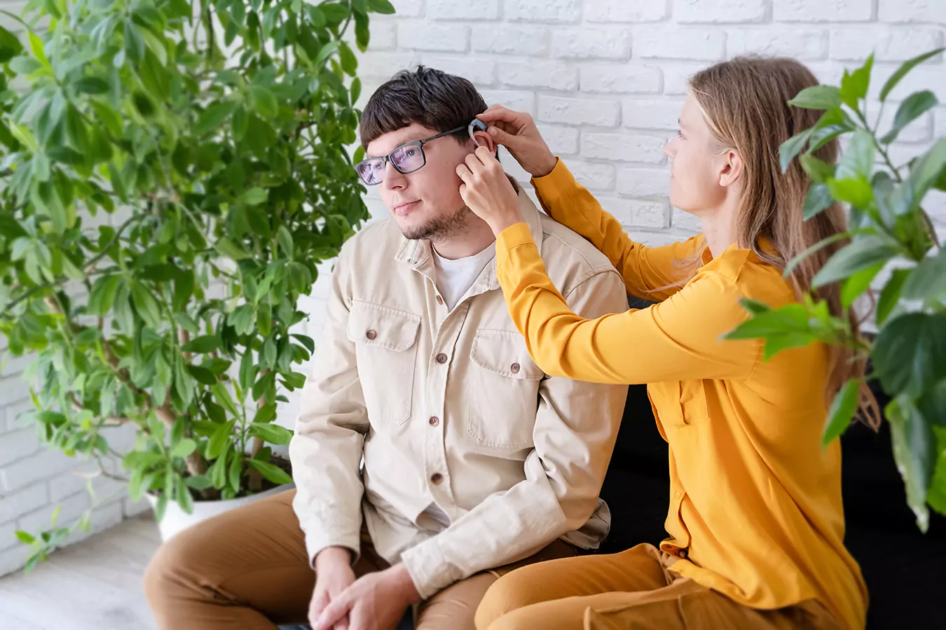 A disabled man and his support worker beside him putting on his ear plugs